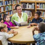 Teacher reading to children in library