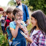 Group of school children with teacher on field trip in nature, learning science.