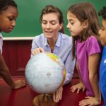 Teacher explaining globe to students in classroom