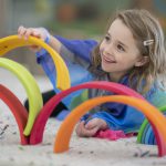 Cute elementary girl building a rainbow structure